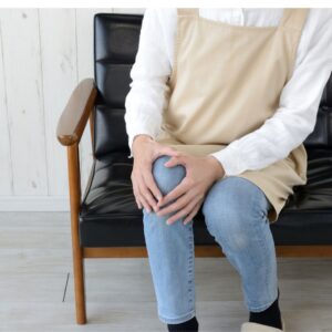 woman sitting on a couch holding her knee in pain